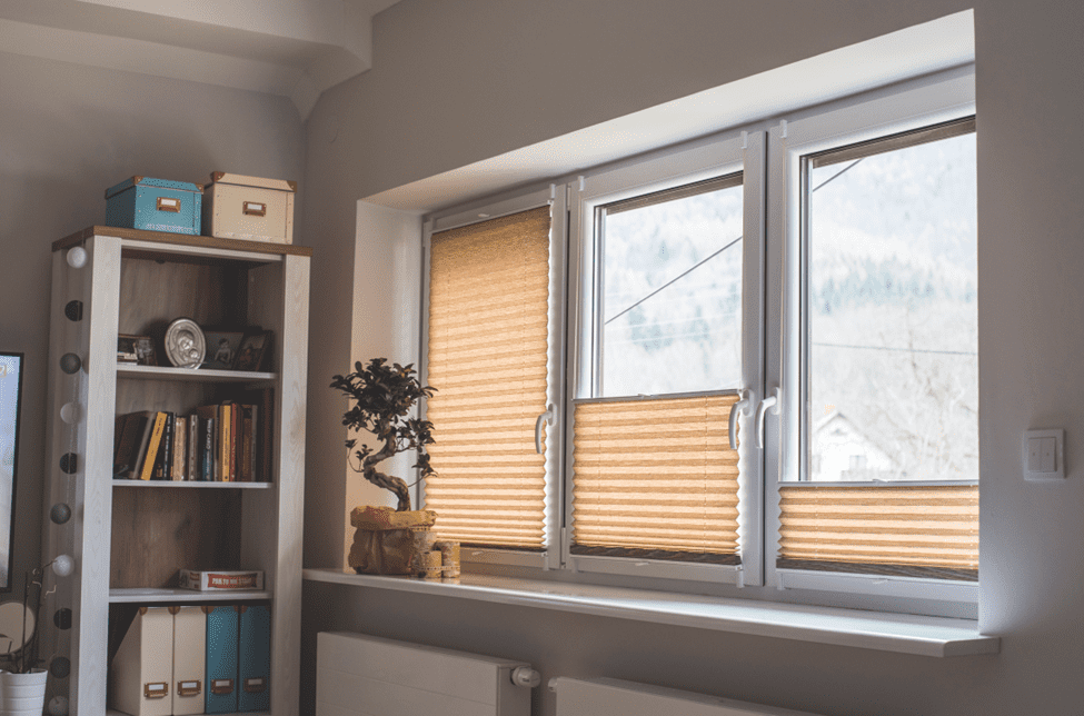 A room with a window with pleated blinds installed.